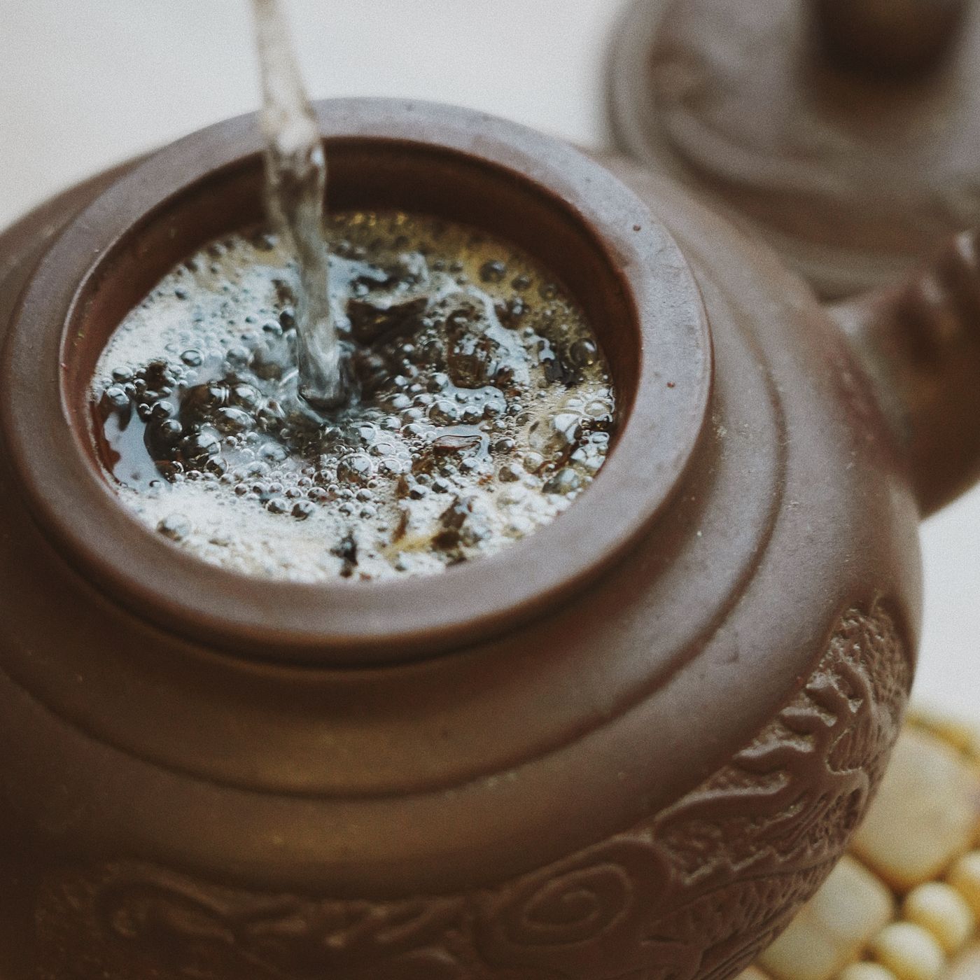 A clay teapot seen from above with herbal tea brewing inside it.