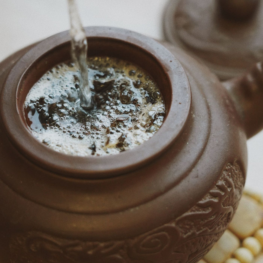 A clay teapot seen from above with herbal tea brewing inside it.
