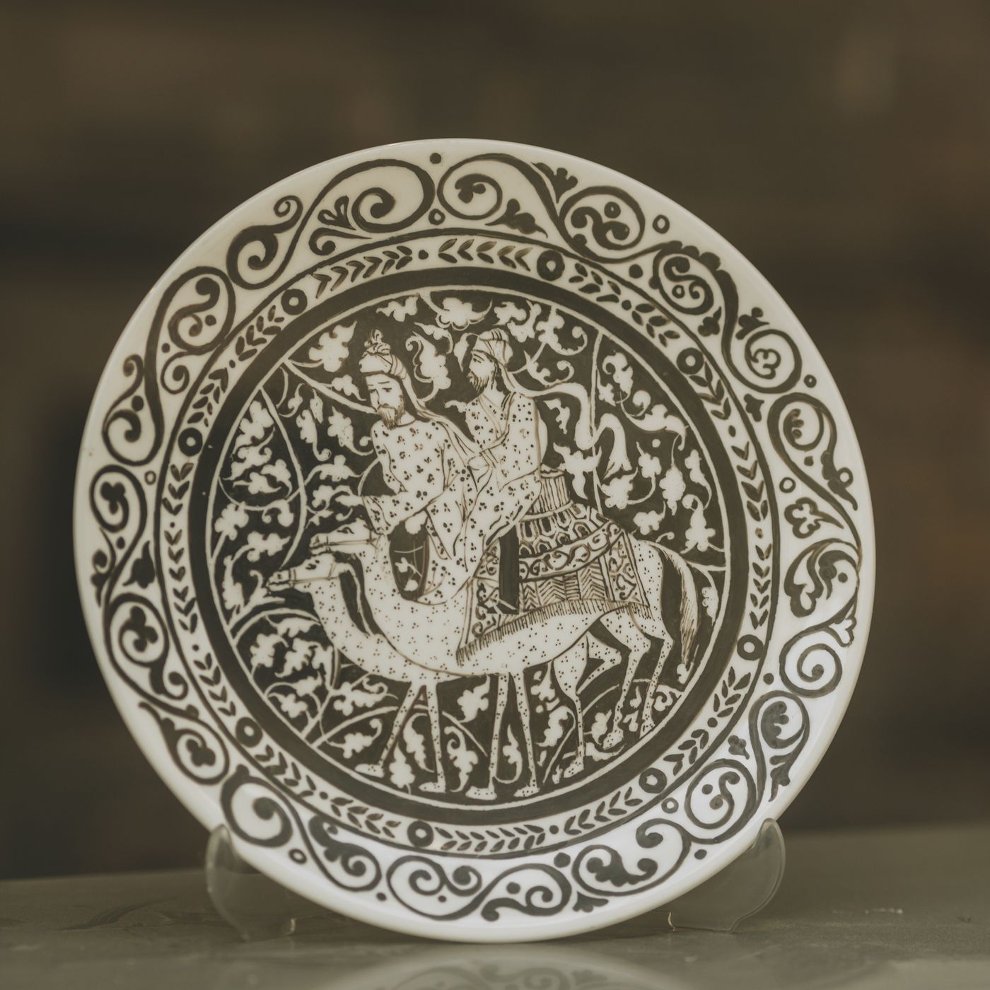A decorative plate covered in elaborate patterns with figures worked into the scene.