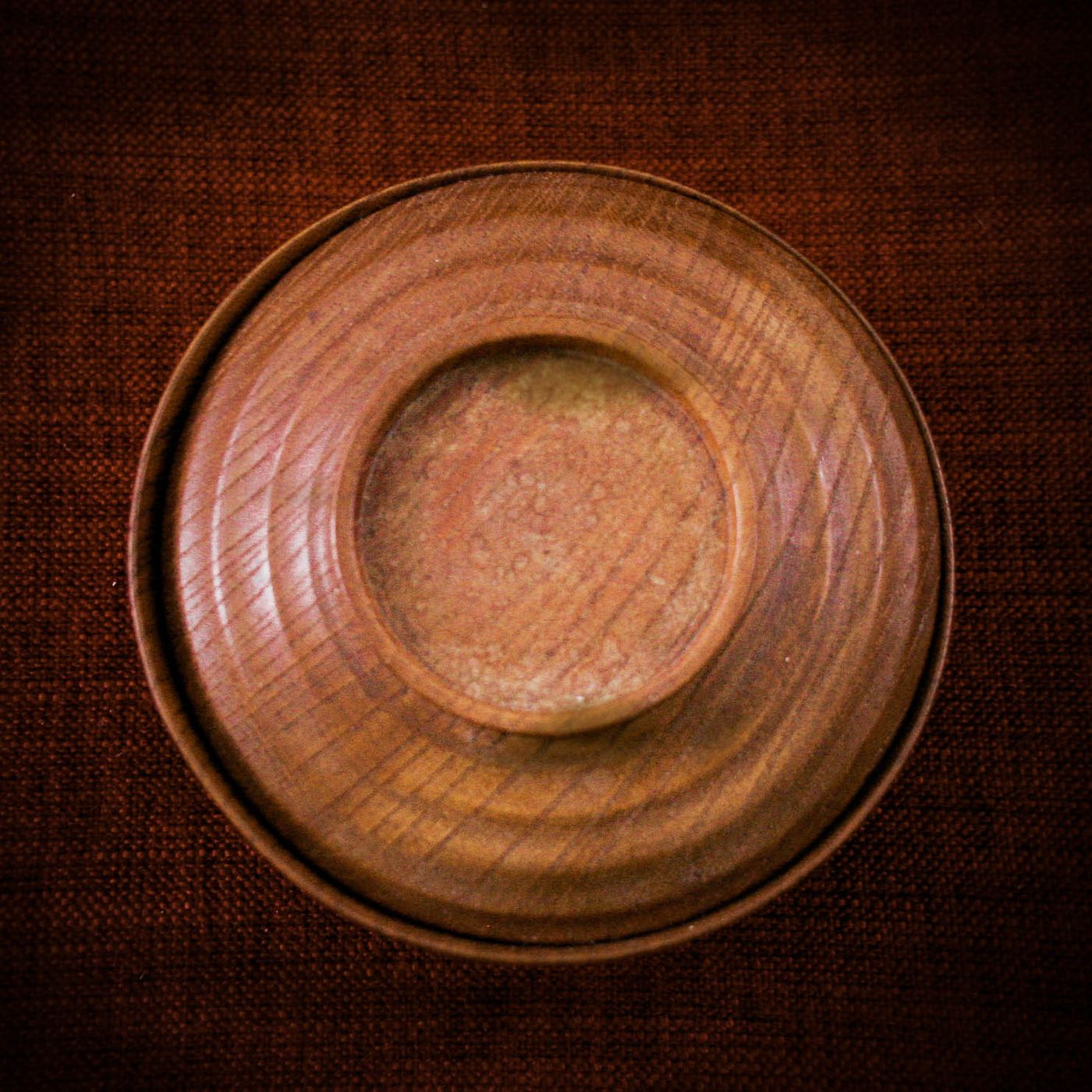A round brown saucer, photographed plainly on its own.
