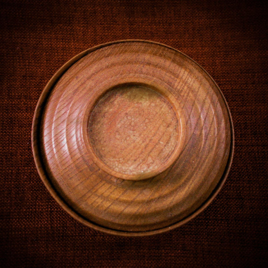 A round brown saucer, photographed plainly on its own.