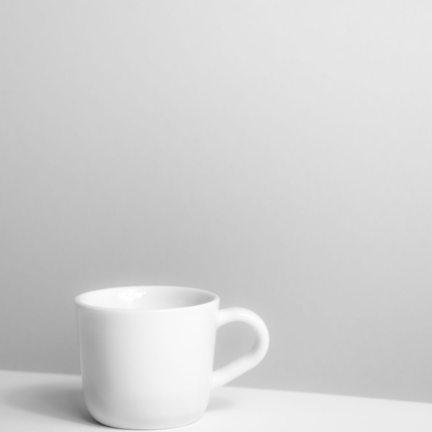 A white porcelain mug photographed in a plain setting under soft directional light.