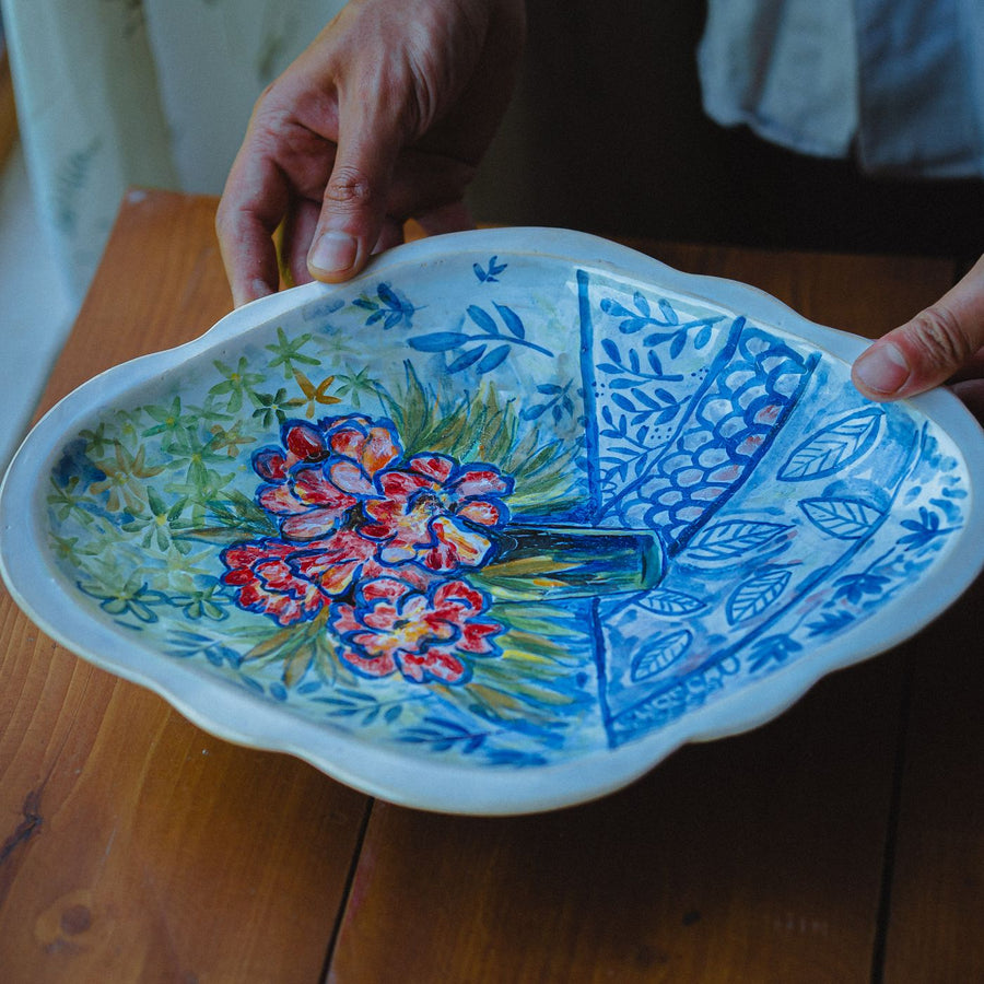 A handmade ceramic plate carrying a floral design.