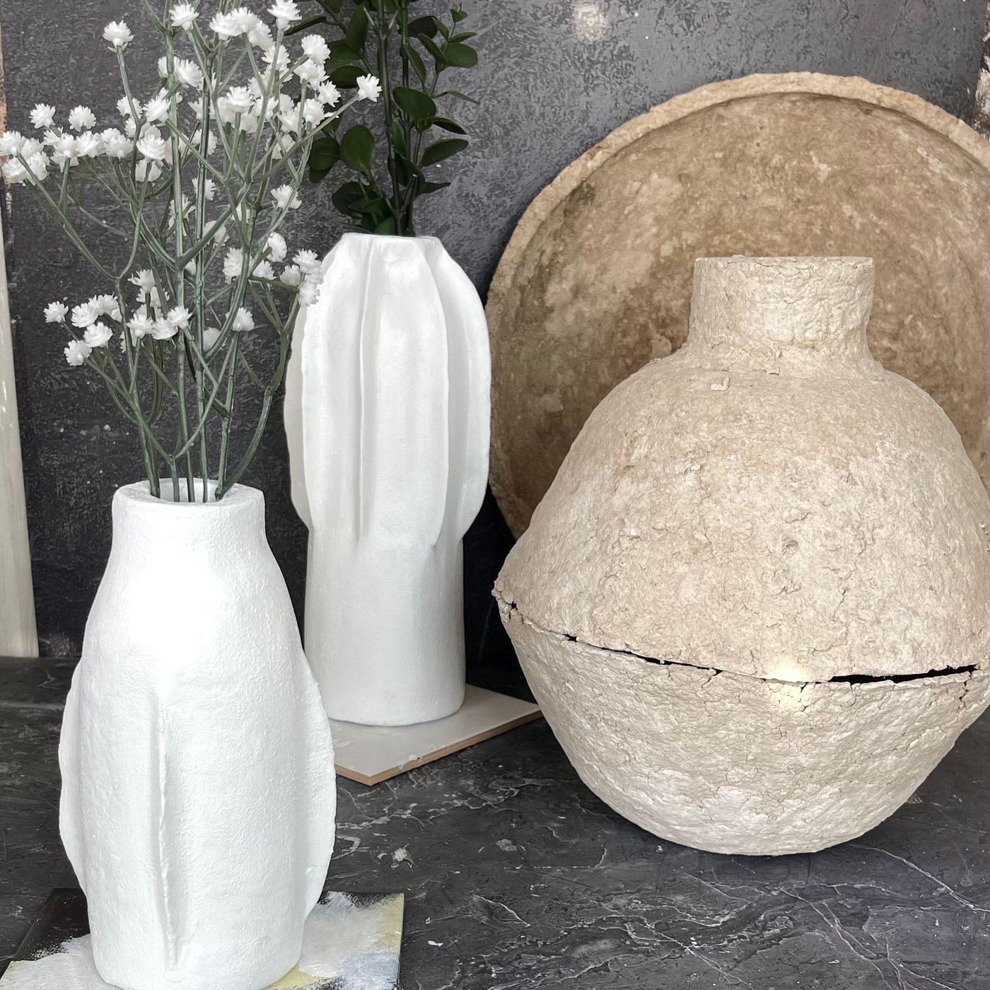 A plain ceramic vase shown on display with nothing arranged in it.