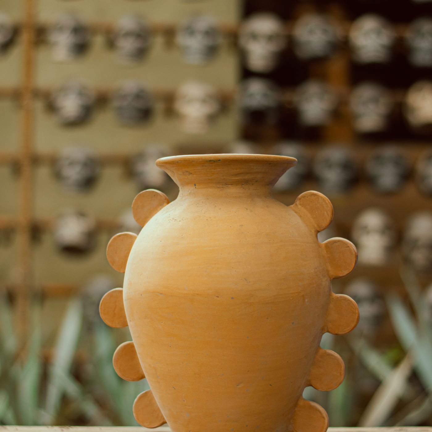 A handmade terracotta vase with its own particular shape, shown on a rustic wooden table.