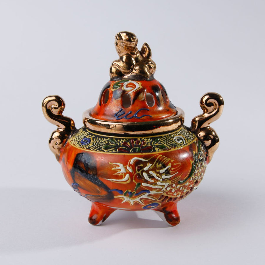 An oriental incense burner carrying a dragon motif in deep rich colours.