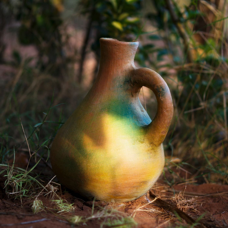 A ceramic jug in earthy colours, photographed outdoors in a natural setting.