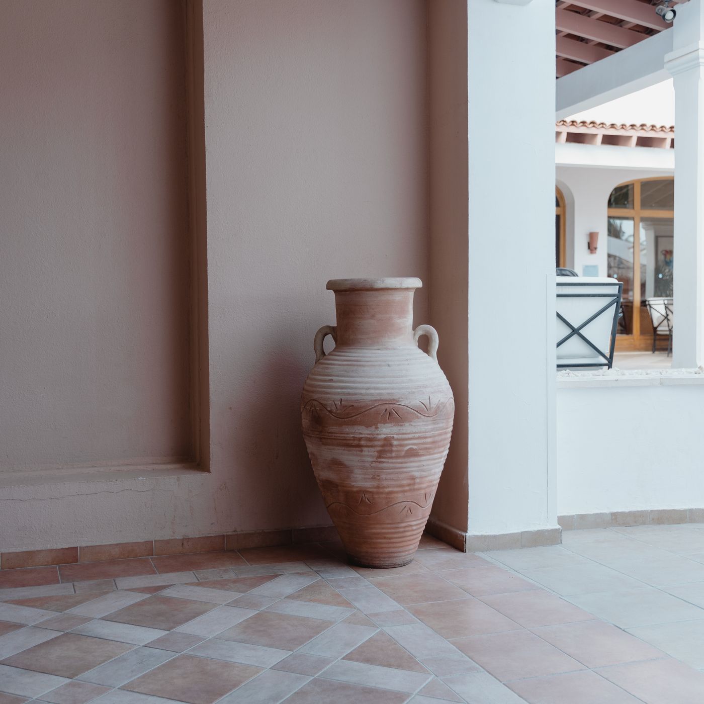 A large clay amphora standing in the corner of a Mediterranean interior.