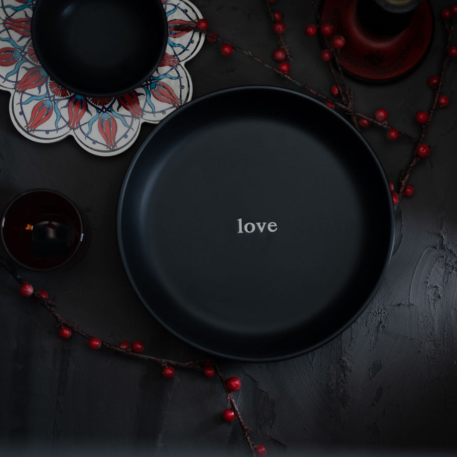 A black plate lettered with the word love, set among decorative elements.