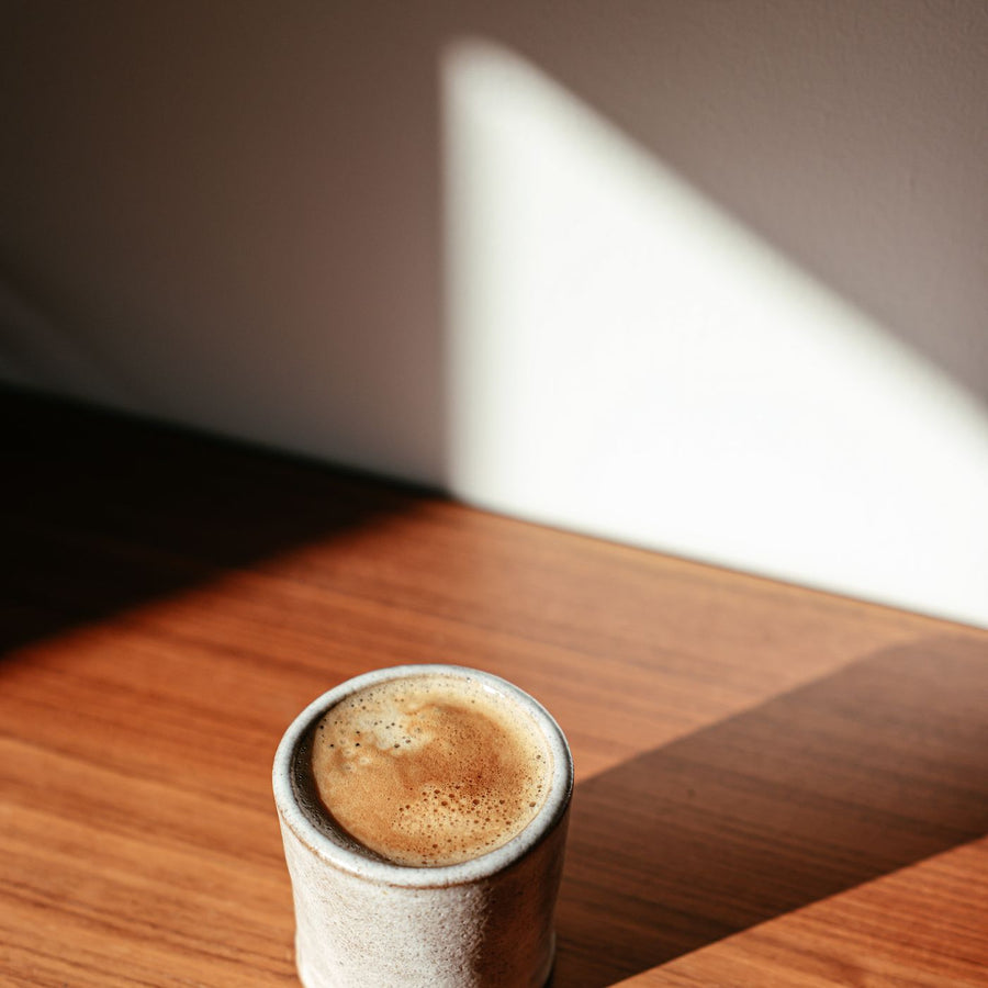 A simple ceramic cup on a wooden table, lit so the shadows stay soft.