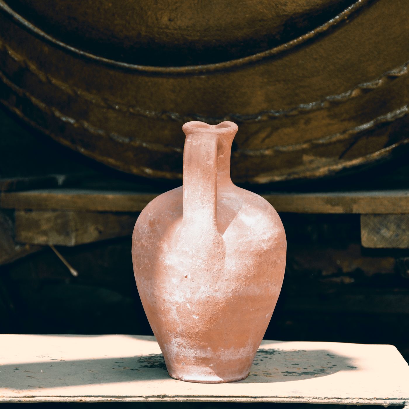 A handmade ceramic vase in earthy colour and texture, photographed in a sunlit workshop.